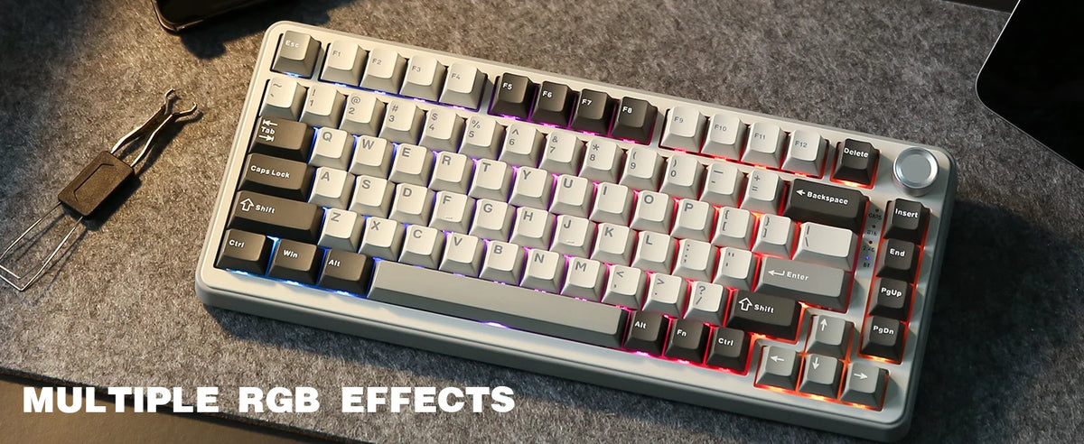 A close-up view of a light gray mechanical keyboard with RGB lighting effects on a dark gray surface.