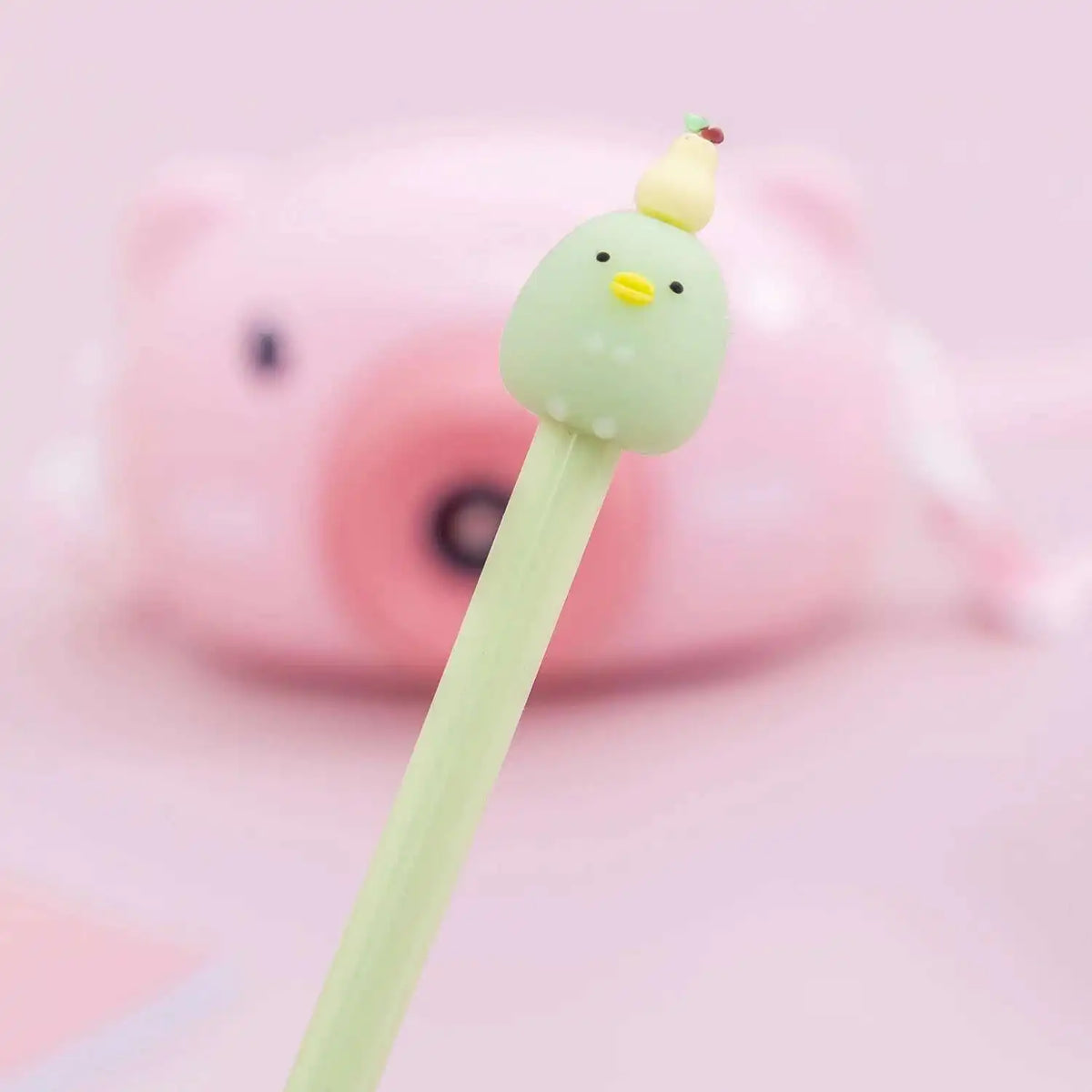 A cute cartoon yellow chick shaped gel pen with a pink body is shown against a light pink background.