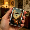 A hand holds a vintage stainless steel card and cash case with a depiction of a flying saucer on it.