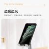 A smartphone is mounted on a foldable desktop stand, showing the screen and charging cable.