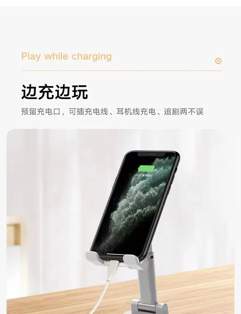 A smartphone is mounted on a foldable desktop stand, showing the screen and charging cable.