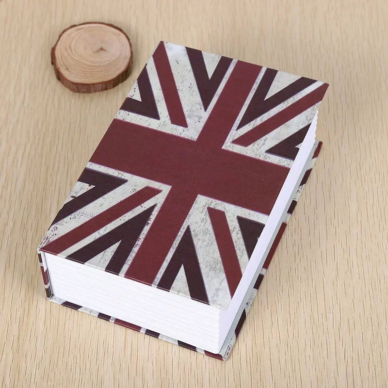 A small book with a British flag pattern cover lying on a wooden surface.