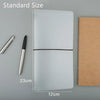 A clear PVC cover for a standard travelers notebook shown next to a pen and a brown notebook.