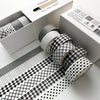 A set of six rolls of plaid, grid, and polka dot washi tape on a white box for crafting and journaling.
