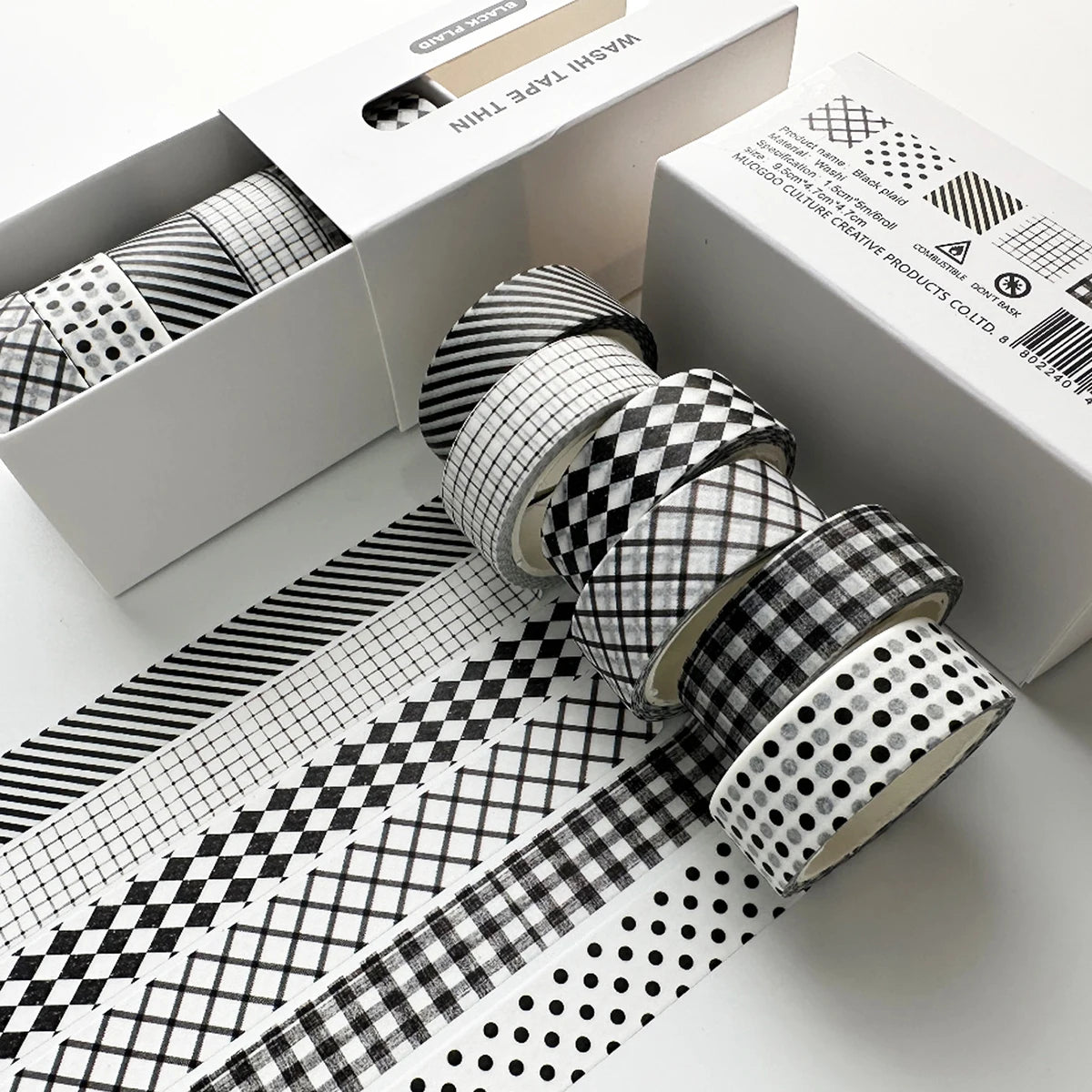 A set of six rolls of plaid, grid, and polka dot washi tape on a white box for crafting and journaling.