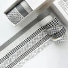 A set of six rolls of plaid, grid, and polka dot washi tape in black and white patterns displayed in a box.