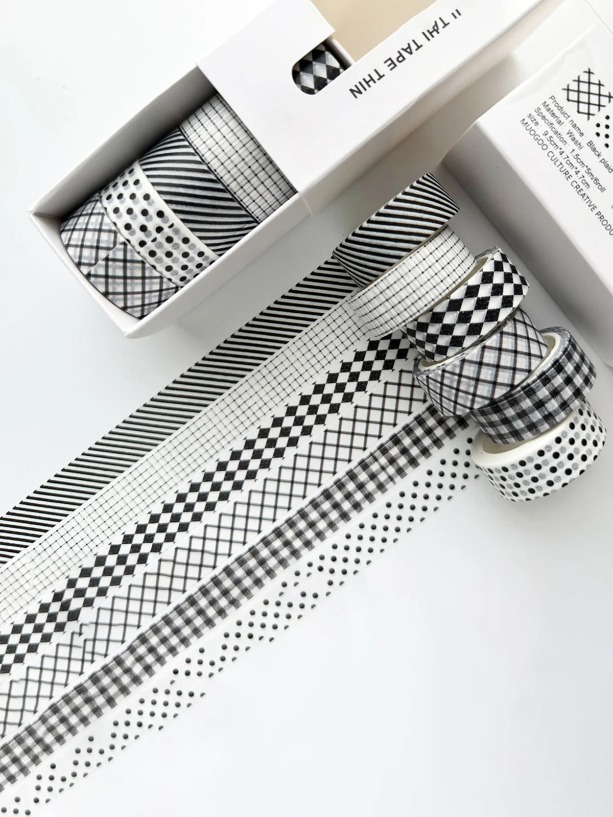 A set of six rolls of plaid, grid, and polka dot washi tape in black and white patterns displayed in a box.