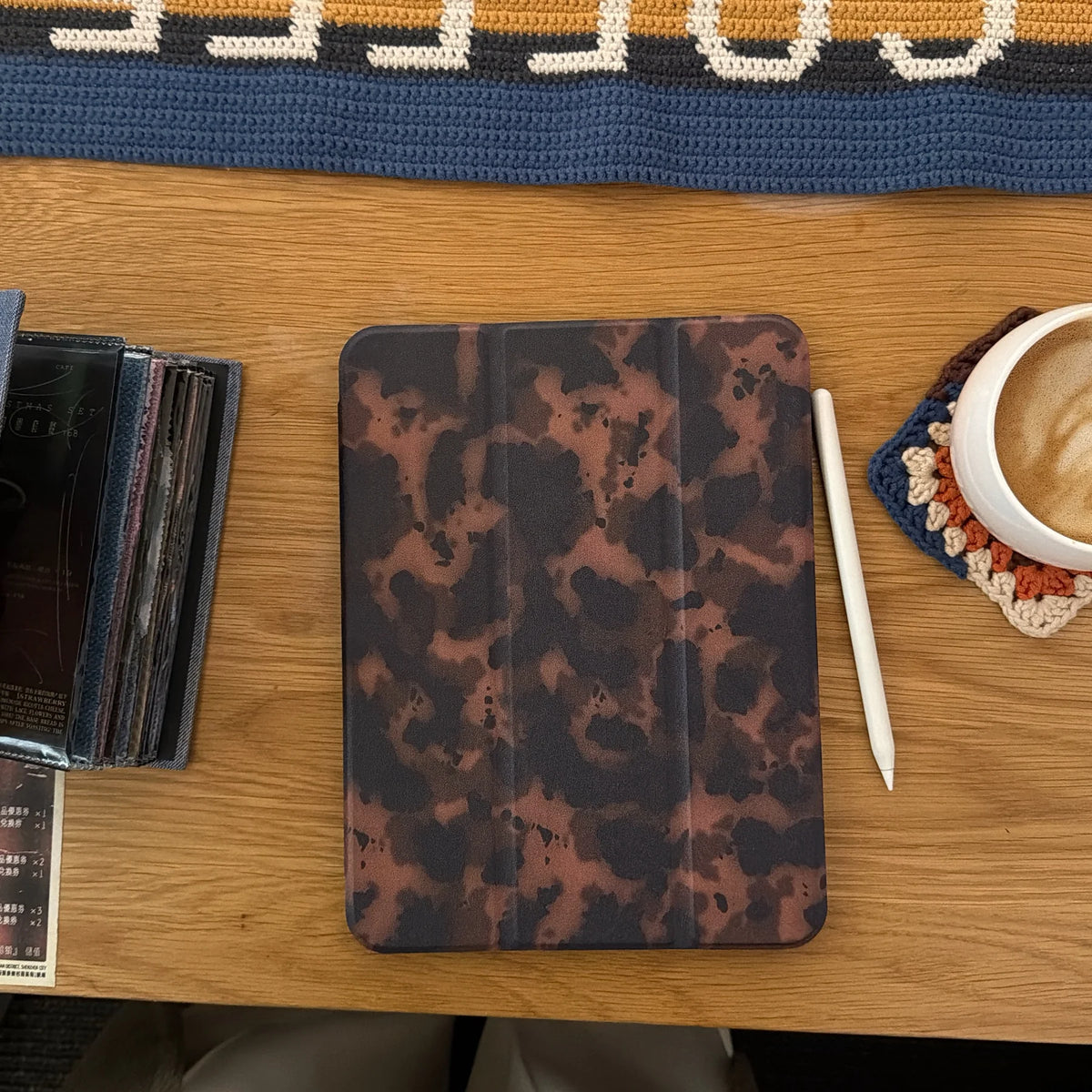 Braunes Leopardenmuster-Leder-Tablet-Cover auf einem Holztablett neben einer weißen Tasse und einem Bleistift.