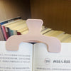 A close-up of pink book page clips with a rounded, ergonomic design resting on the edge of an open book.