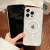 A hand holds a clear magnetic transparent phone case, featuring an Apple-style design, on a wooden surface.