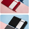 A stack of premium PU leather journal notebooks in red and black colors displayed on a light pink surface.