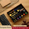 A wooden box containing a luxury fountain pen set and wax seal kit with various tools on a wooden surface.