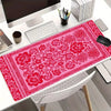A vibrant pink vintage Persian rug gaming mouse pad with a non-slip rubber base placed on a white desk.