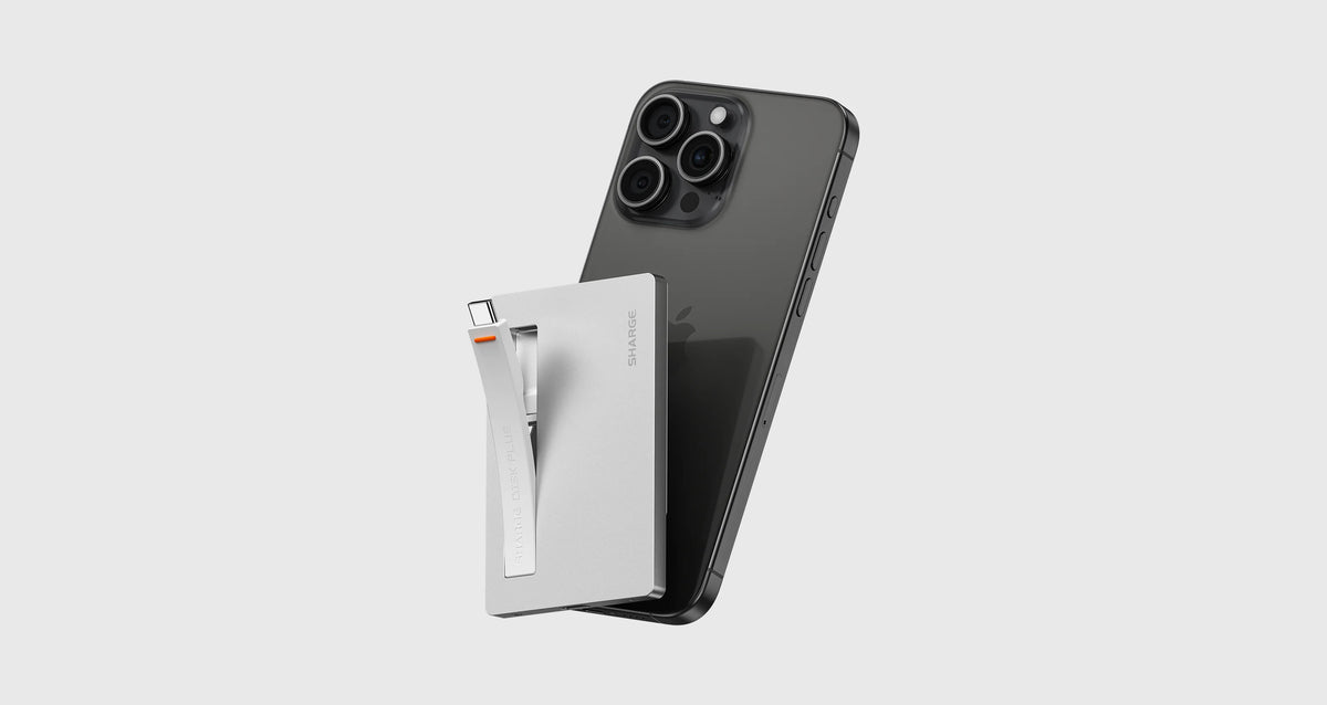 Silberner tragbarer NVMe SSD-Gehäuse mit einem schwarzen Smartphone auf hellem grauem Hintergrund.