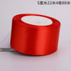 A roll of red satin ribbon with white fluff visible on top.