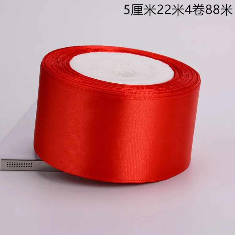 A roll of red satin ribbon with white fluff visible on top.