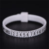 A white precision ring sizer tool with numbered markings is shown on a dark surface.