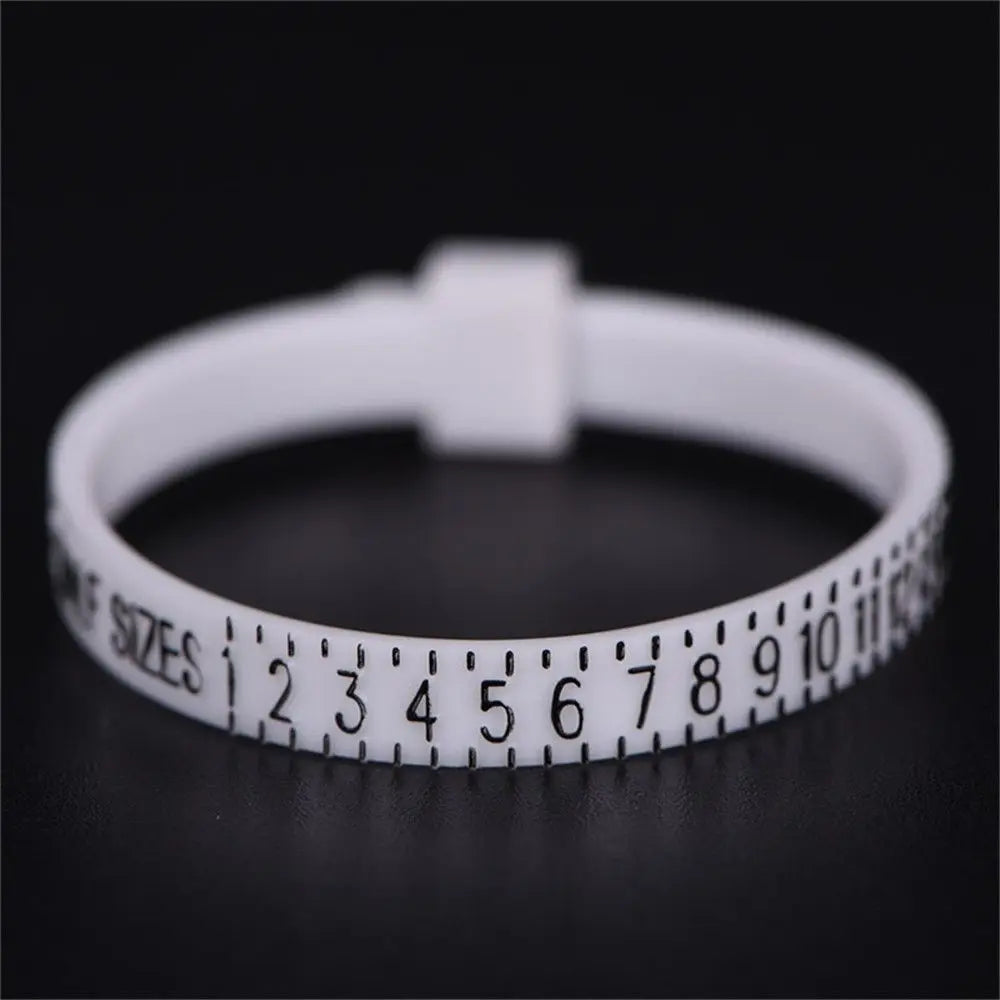 A white precision ring sizer tool with numbered markings is shown on a dark surface.