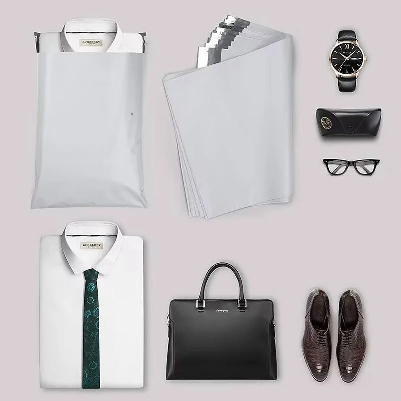 A collection of white and black courier mailer bags, a black leather wallet, and sunglasses displayed on a light gray backgro