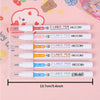 A set of six dual-color line marker pens in clear plastic packaging displayed on a pink background.
