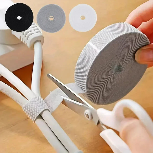 A hand is using pliers to remove a reusable hook and loop cable tie from a white wire, with several circular ties shown.