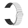 A close-up view of a white and black adjustable magnetic loop watch band.