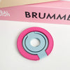 A pink and light blue magnetic phone grip and stand with a foldable ring resting on a white surface.