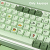 A close-up view of light green PBT keycaps for a mechanical keyboard, showing various letter and symbol keys.