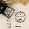 A black self-inking stamp is shown resting on a spiral notebook page, with a circular logo for 'Hally & Mark' and space for c