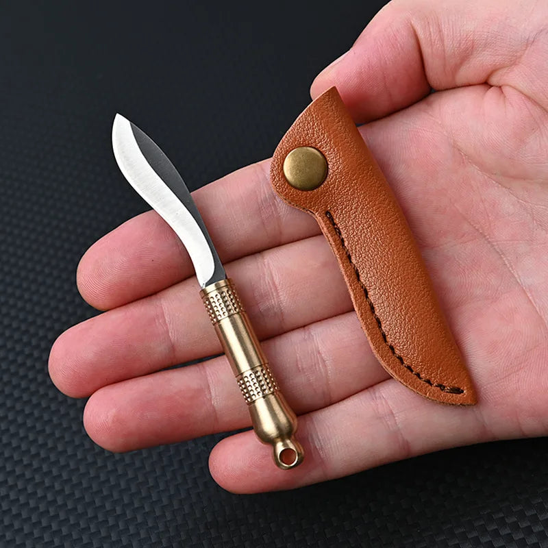 A compact fixed blade knife with a silver blade and brass tang is shown next to its brown leather sheath in a hand.