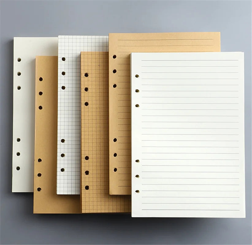 Una pila de resmas de cuadernos sueltos de varios colores, incluyendo tonos blancos, beige y amarillos.