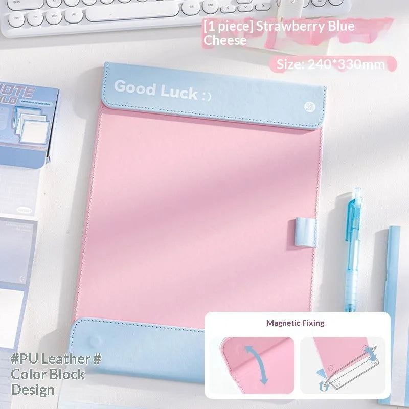 A pink A4 leather clipboard with a blue magnetic closure and contrast stitching, featuring a Good Luck message.