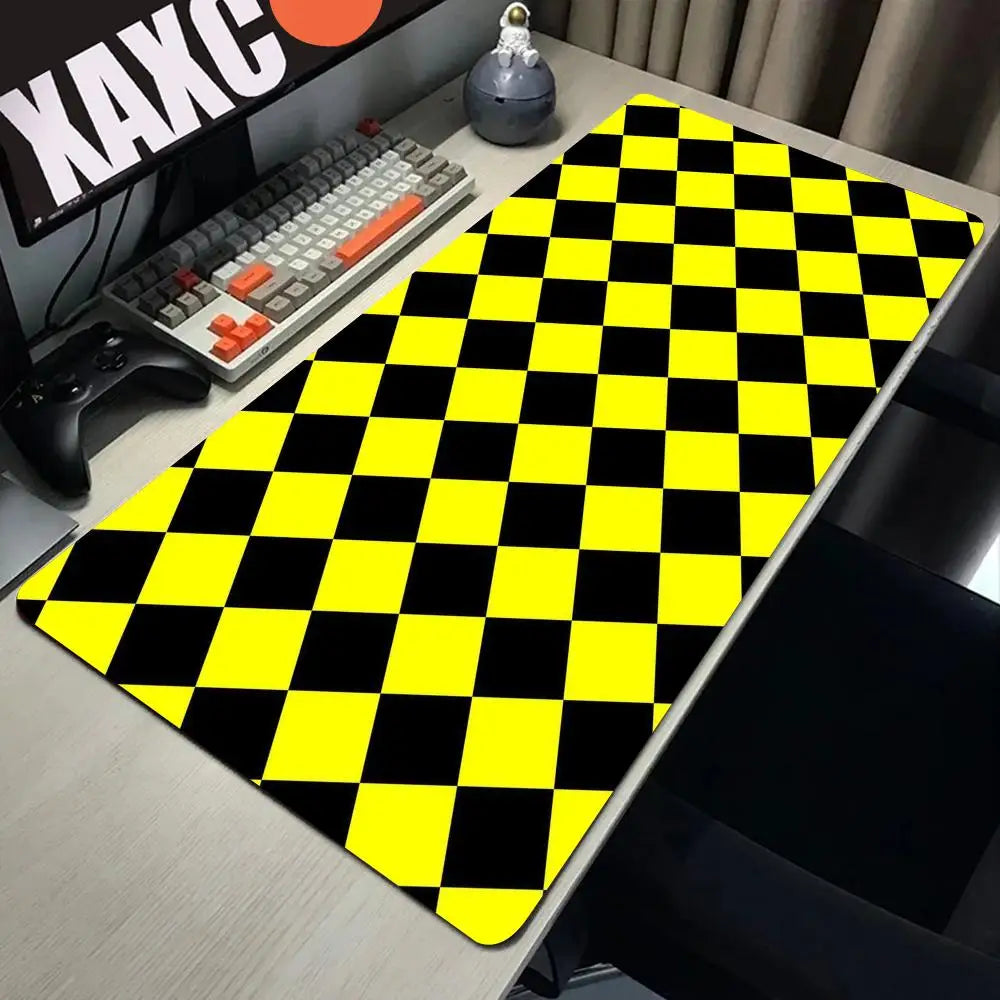A yellow and black checkered desk mat is placed on a wooden desk next to a keyboard and gaming controller.