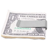 A rolled US one dollar bill is shown with a stainless steel money clip placed on top.