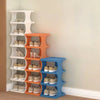 A display of portable plastic shoe hangers in white, orange, and blue on a light wall.