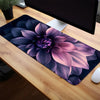 A floral mouse pad featuring a purple and pink peony design placed on a wooden desk.