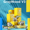 A close-up of the GrayWood V3 linear mechanical keyboard switches displayed on a yellow stand against a blue background.