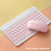 A pink wireless mouse and keyboard set placed on a light orange surface.
