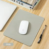 A gray portable gaming mouse pad with a white Apple mouse is shown on a wooden surface.