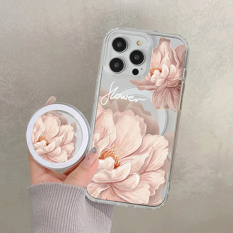 A hand holds a clear floral magnetic phone case for an iPhone featuring pink peony designs.