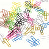 A collection of cross-shaped metal paper clips in various colors including yellow, green, pink, black, and blue.
