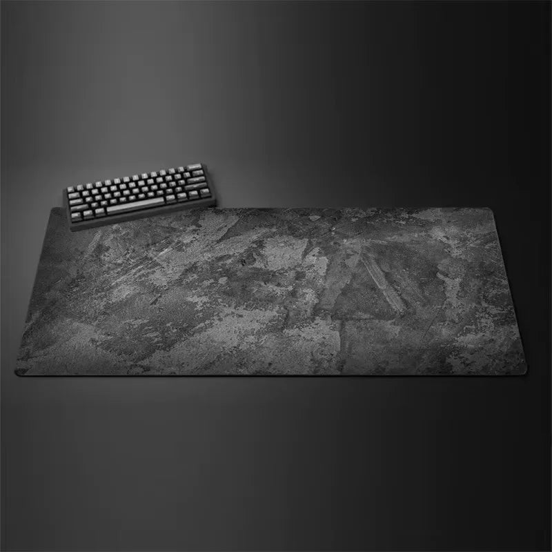 A gray overlocked mouse pad with a black keyboard resting on its surface.