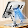 A silver tablet stand with a rotating mechanism is shown illuminating a device on a wooden surface.