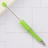 A bright lime green DIY beadable pen with a silver band and a pointed tip resting on a white surface.
