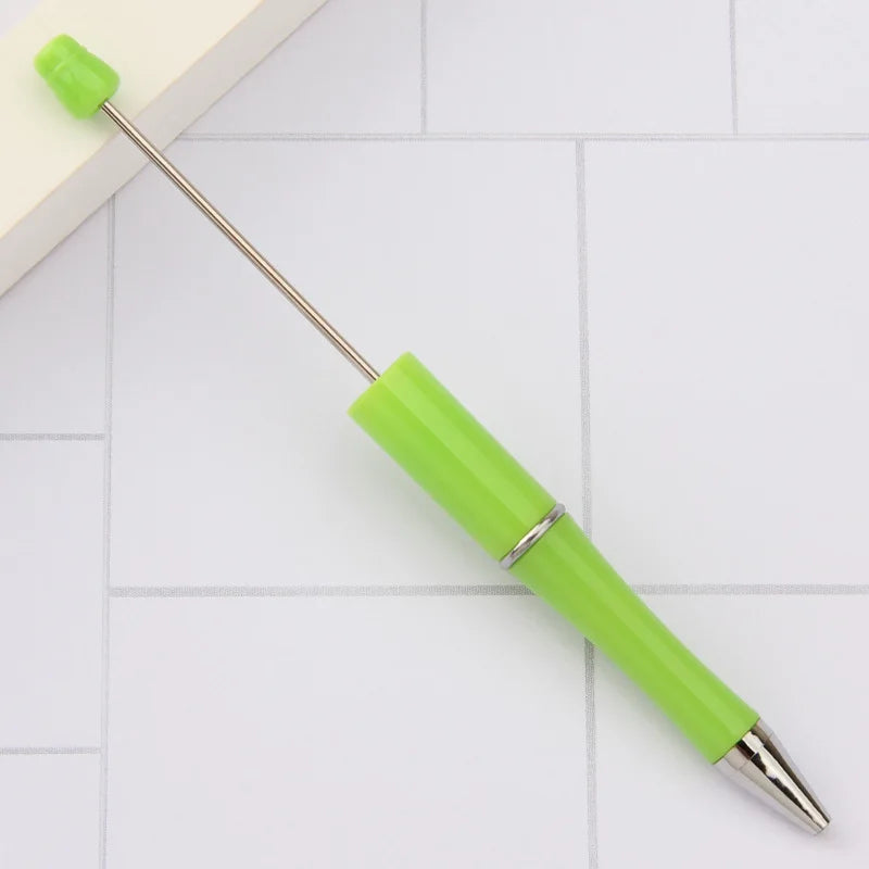 A bright lime green DIY beadable pen with a silver band and a pointed tip resting on a white surface.
