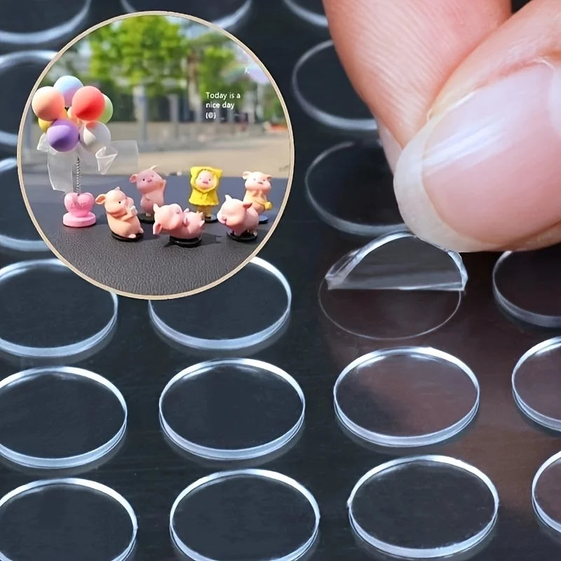 A close-up shot of small pink and purple adhesive dots arranged on a dark surface, with a hand holding a clear plastic piece.