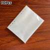 A stack of 10 clear plastic photo card binder sleeves resting on a wooden surface.