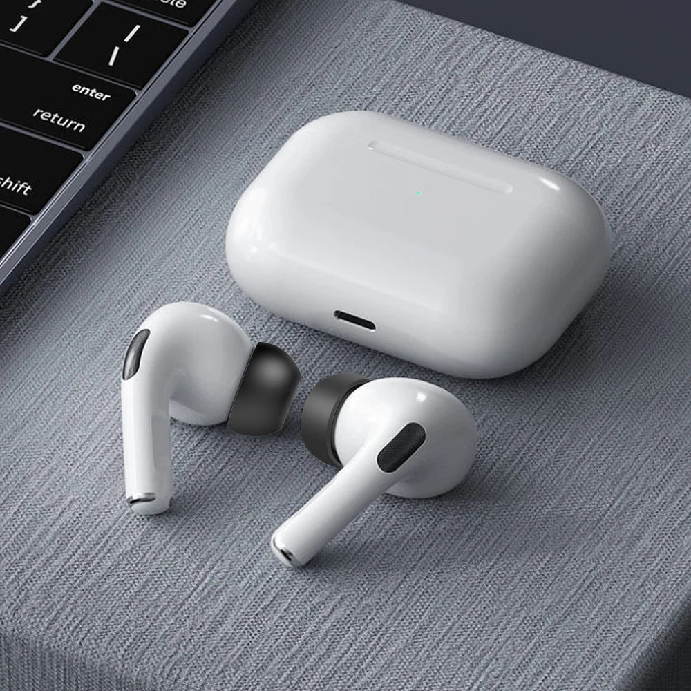 Une coque blanche pour AirPods Apple et des embouts en silicone de rechange sont présentés sur une surface grise.