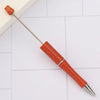 A DIY beadable pen set with an orange-red body and silver tip is shown on a white surface.