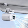 A white clip-on car fan is shown mounted to a ceiling, emitting a bright light beam.